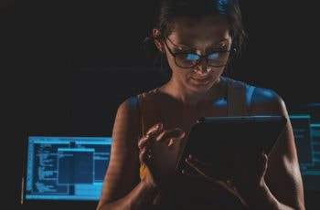 Mujer utilizando una tablet en una habitación con ordenadores.
