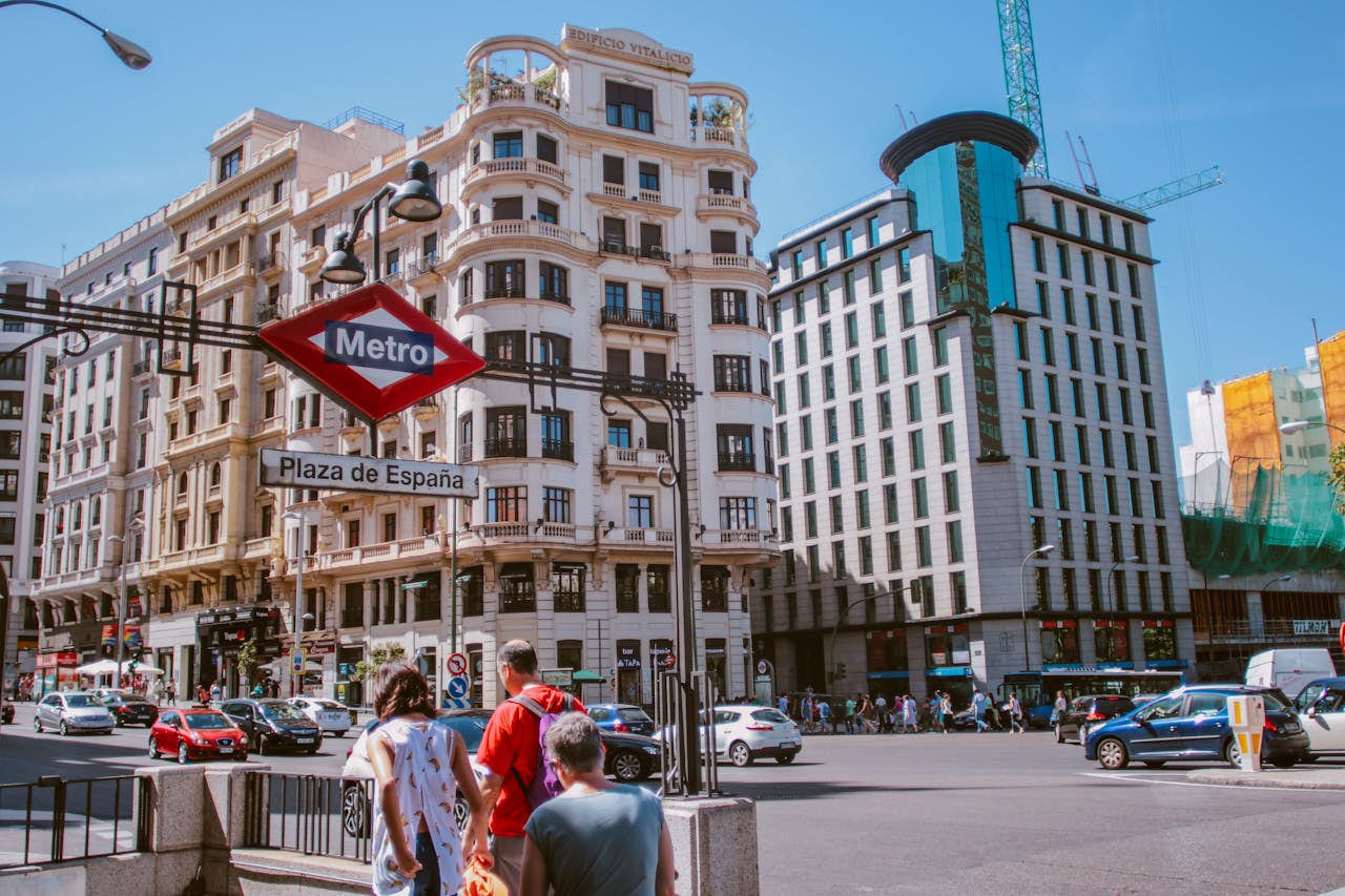 Boca de metro Plaza España junto a dos grandes edificios en Madrid.