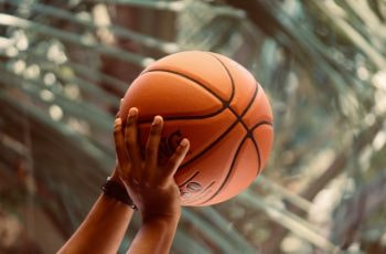 Manos en alto sosteniendo una pelota de baloncesto.