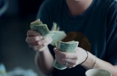 Joven con billetes de dólar en la mano.