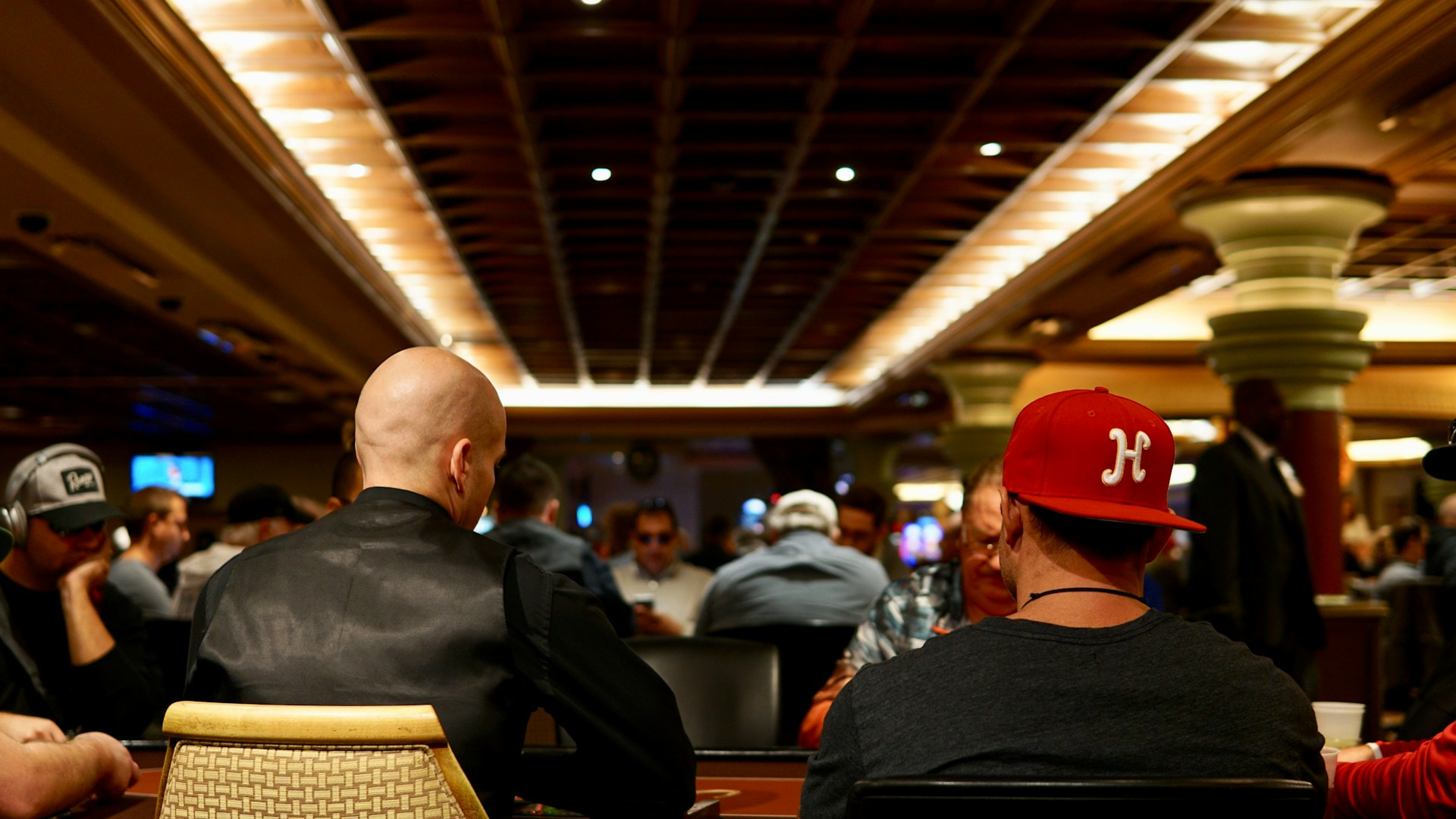 Hombres jugando partidas en mesas de un casino.