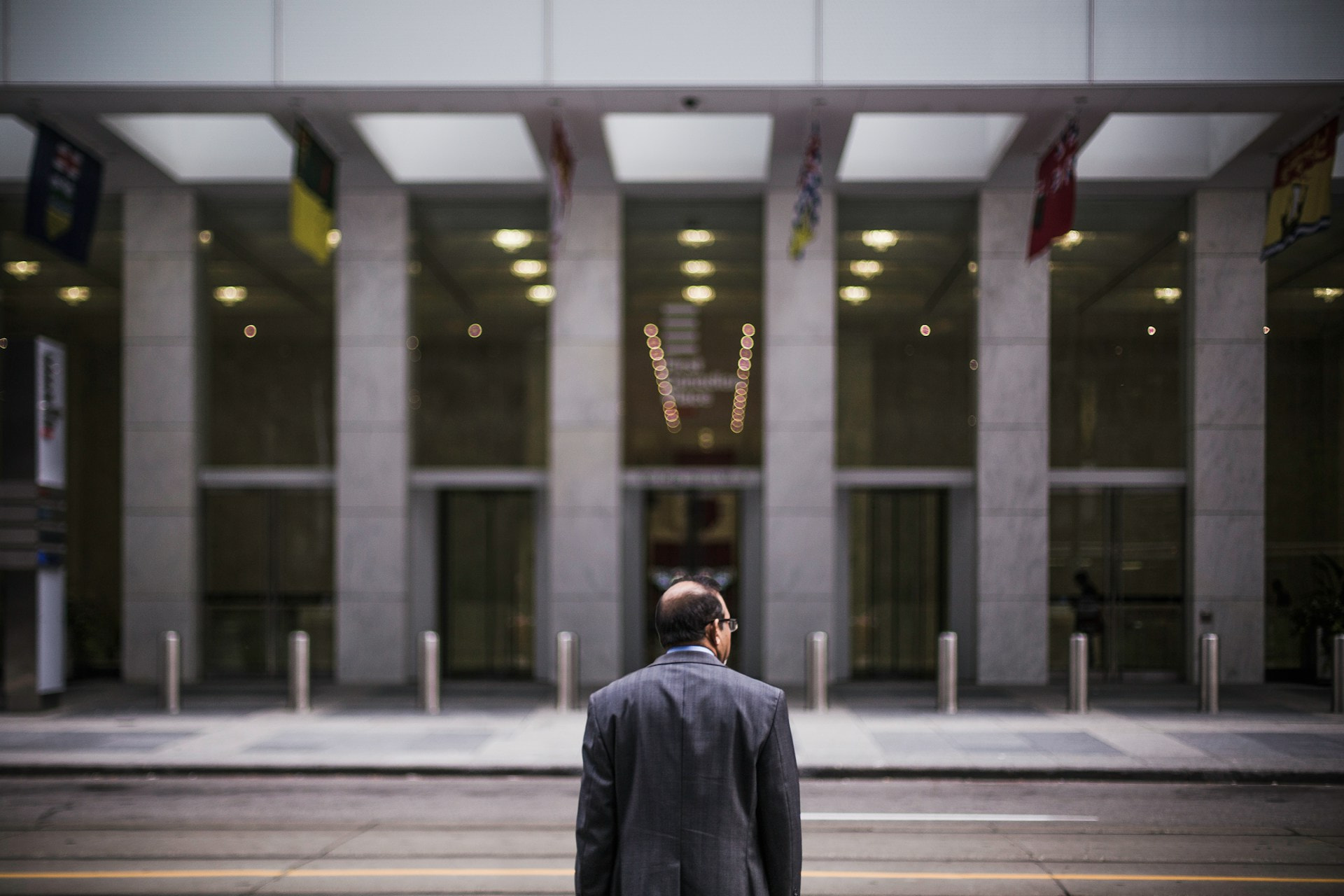 Hombre de pie frente a un edificio de oficinas financieras.