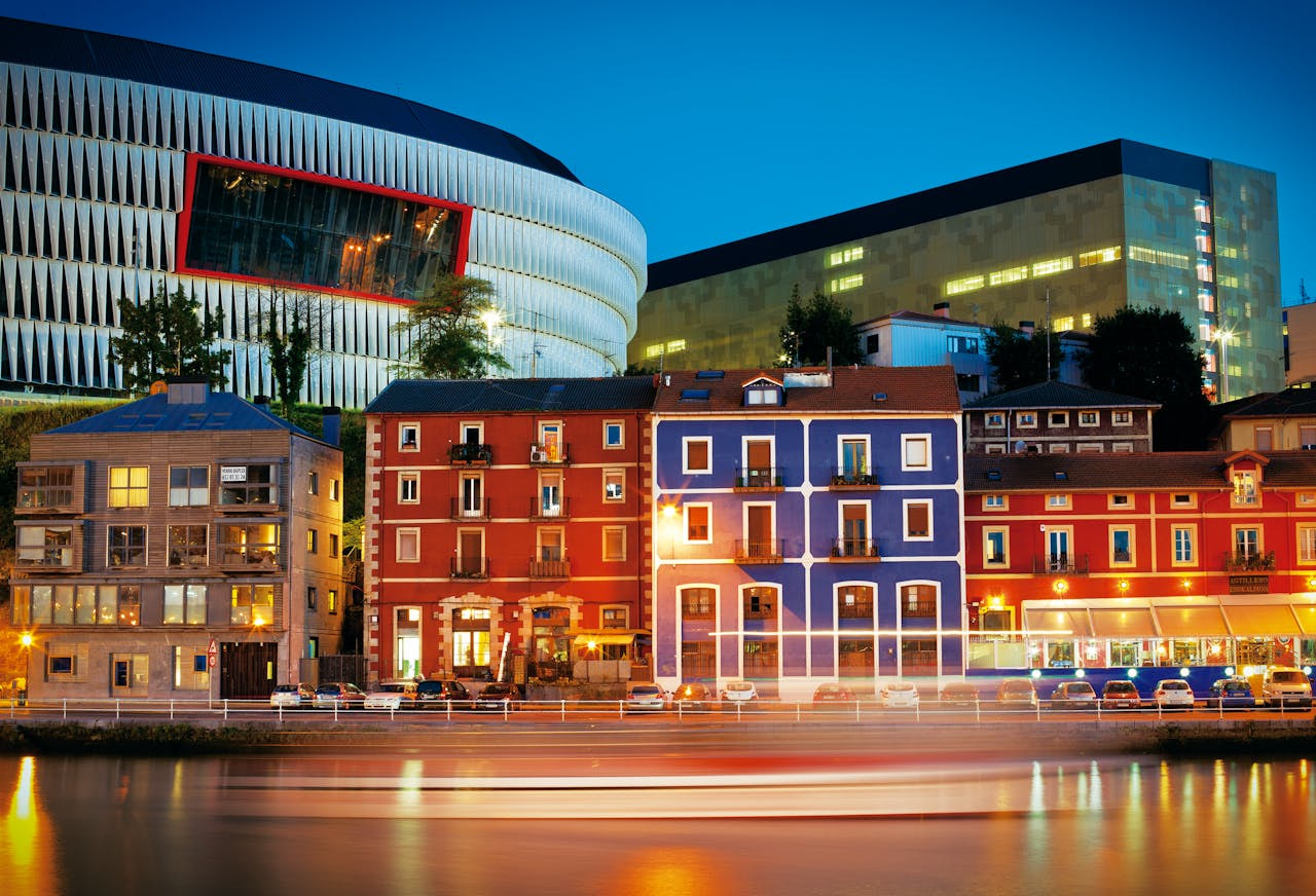 Paseo fluvial en Bilbao con edificios y el estadio San Mamés.